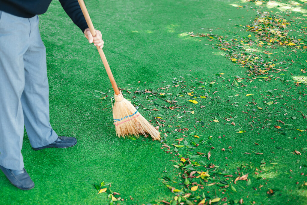 A man brushing an artificial lawn