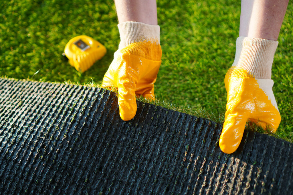 A worker pulling a sheet of artificial grass