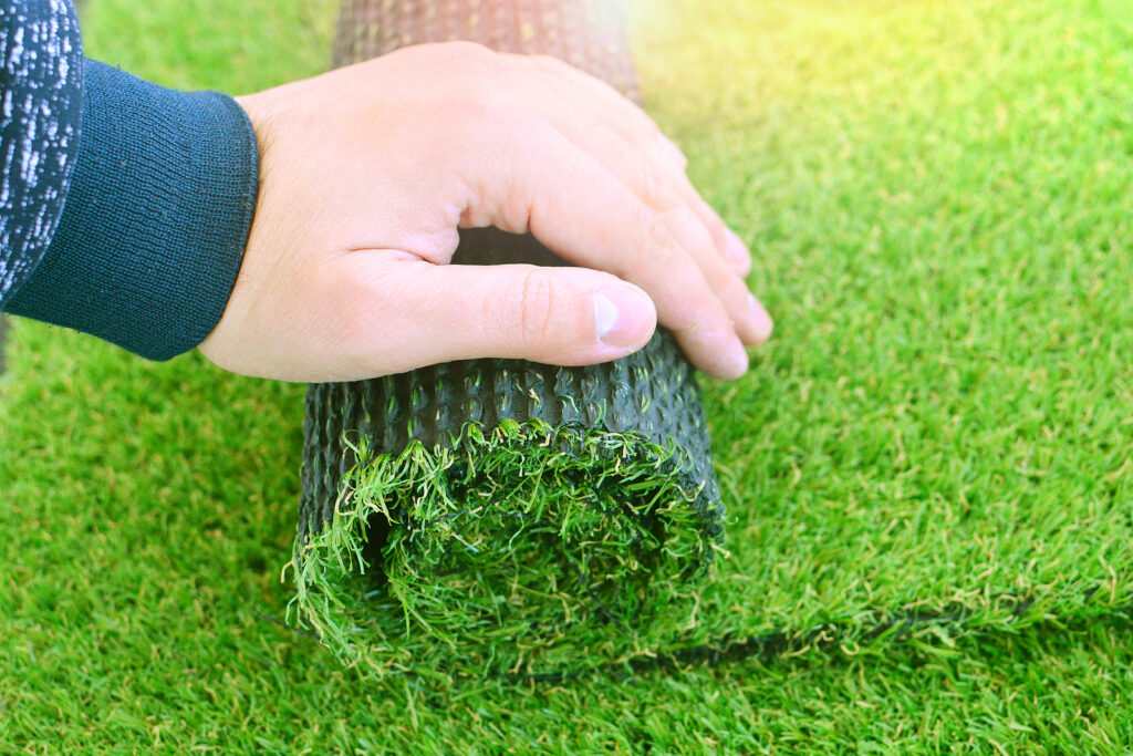 A worker rolling out a strip of artificial grass