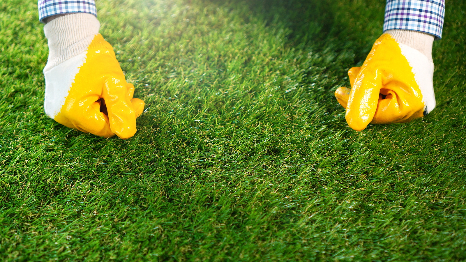 A worker pressing down artificial grass