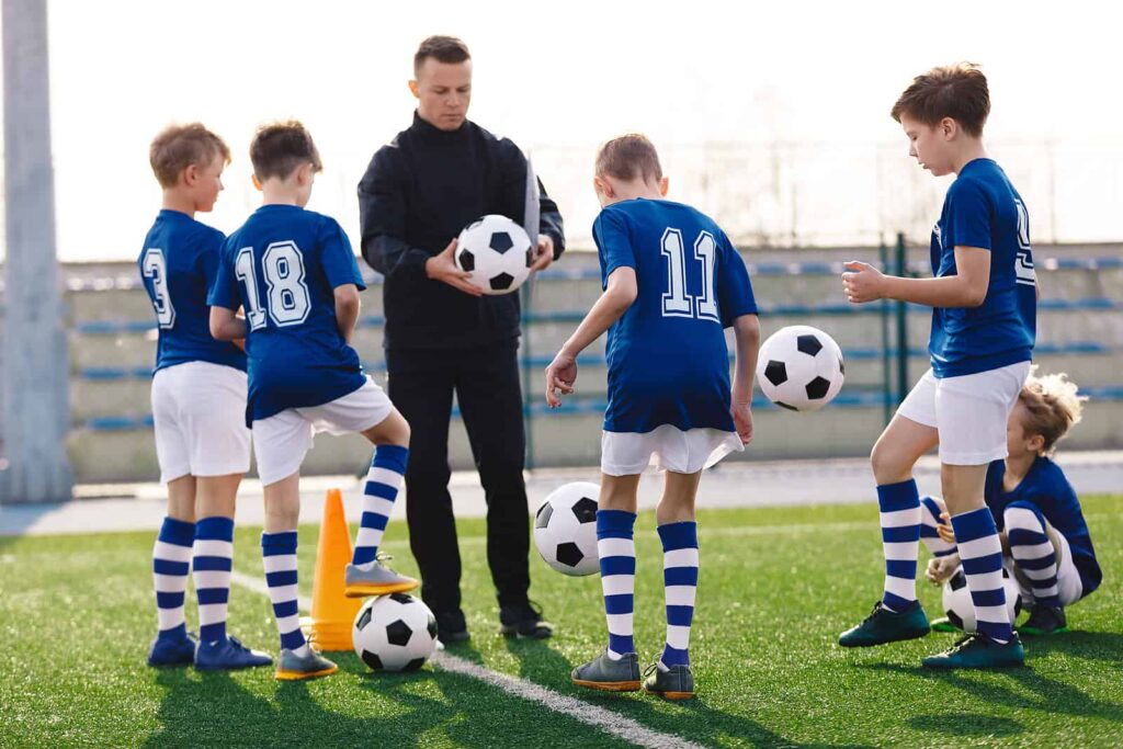 a coach teaching kids how to play football in school pe