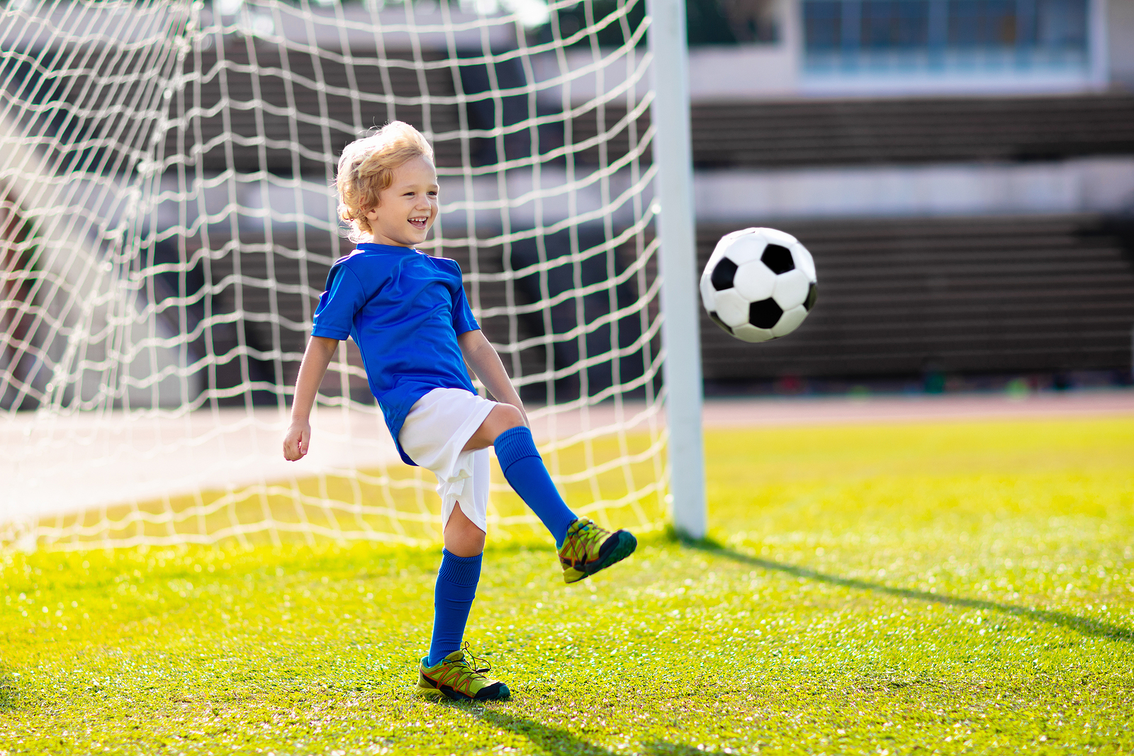 a kid in a football goal defending an oncoming shot at goal