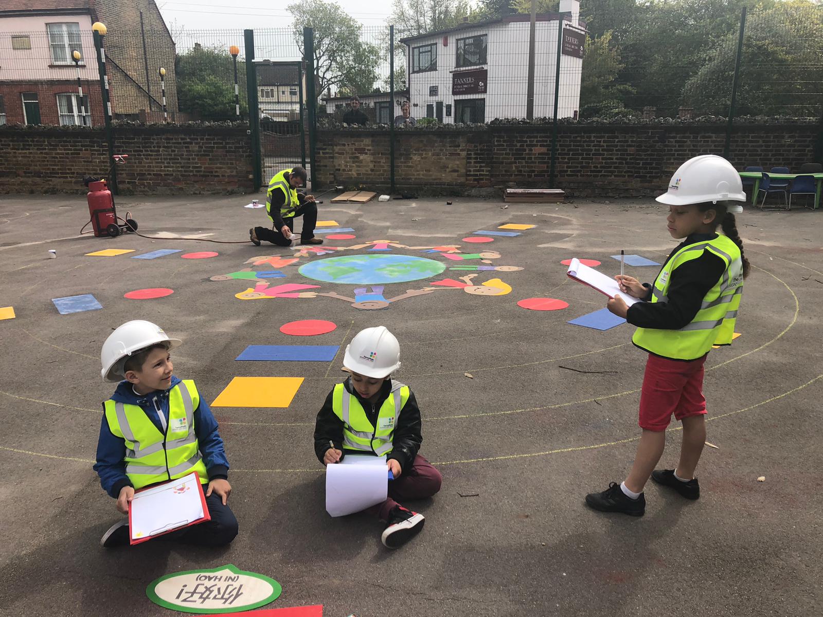 children on the playground wearing hard hats and filling in survey forms